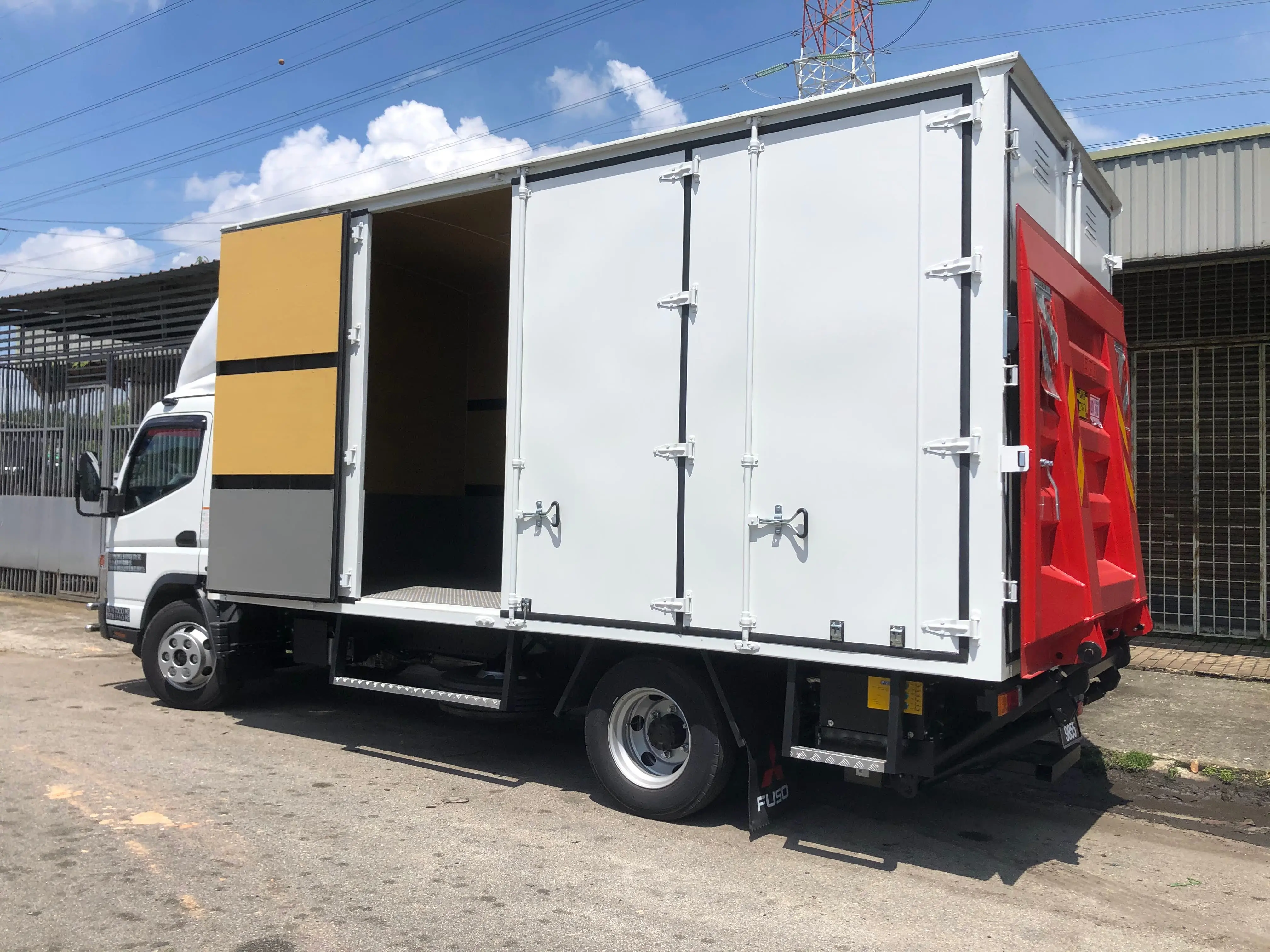 Side view of a Mileford lorry with its hydraulic tailgate lowered for easy loading and unloading.